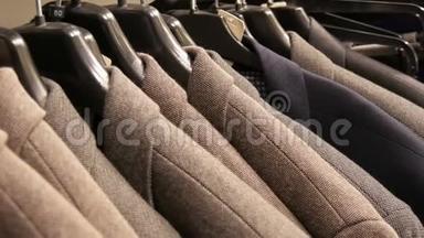 在商场的一家<strong>男士服装</strong>店，一排暖男`夹克衫在衣架上。 各种男士`西装挂在购物中心
